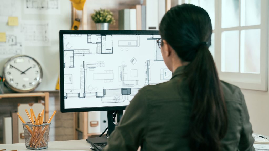 Woman looking at blueprints on computer monitor