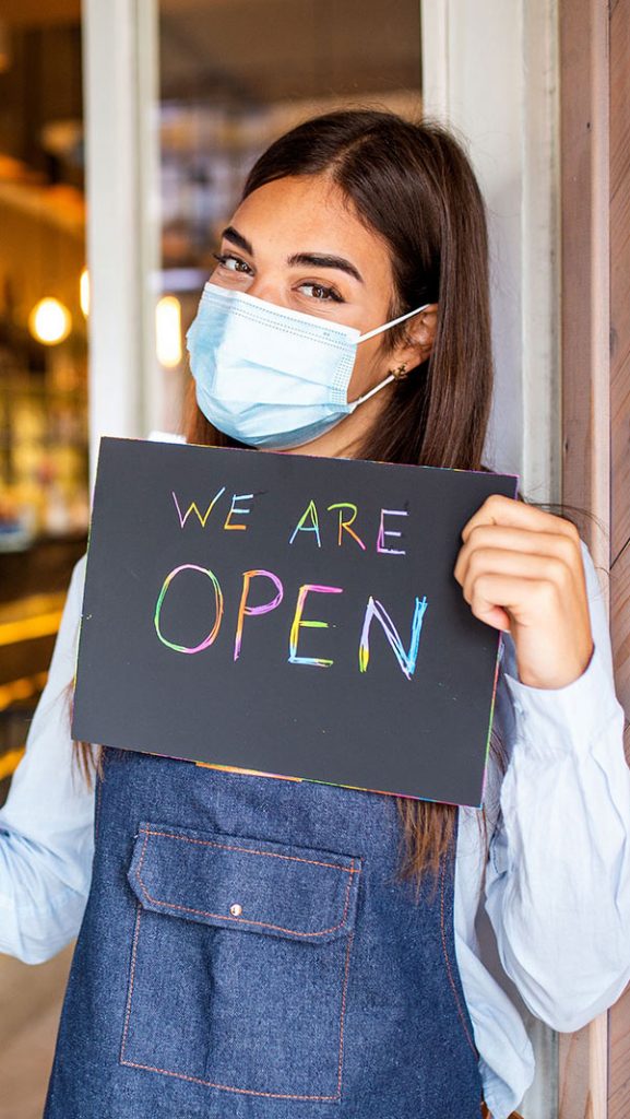 Woman holding an open sign at a restaurant