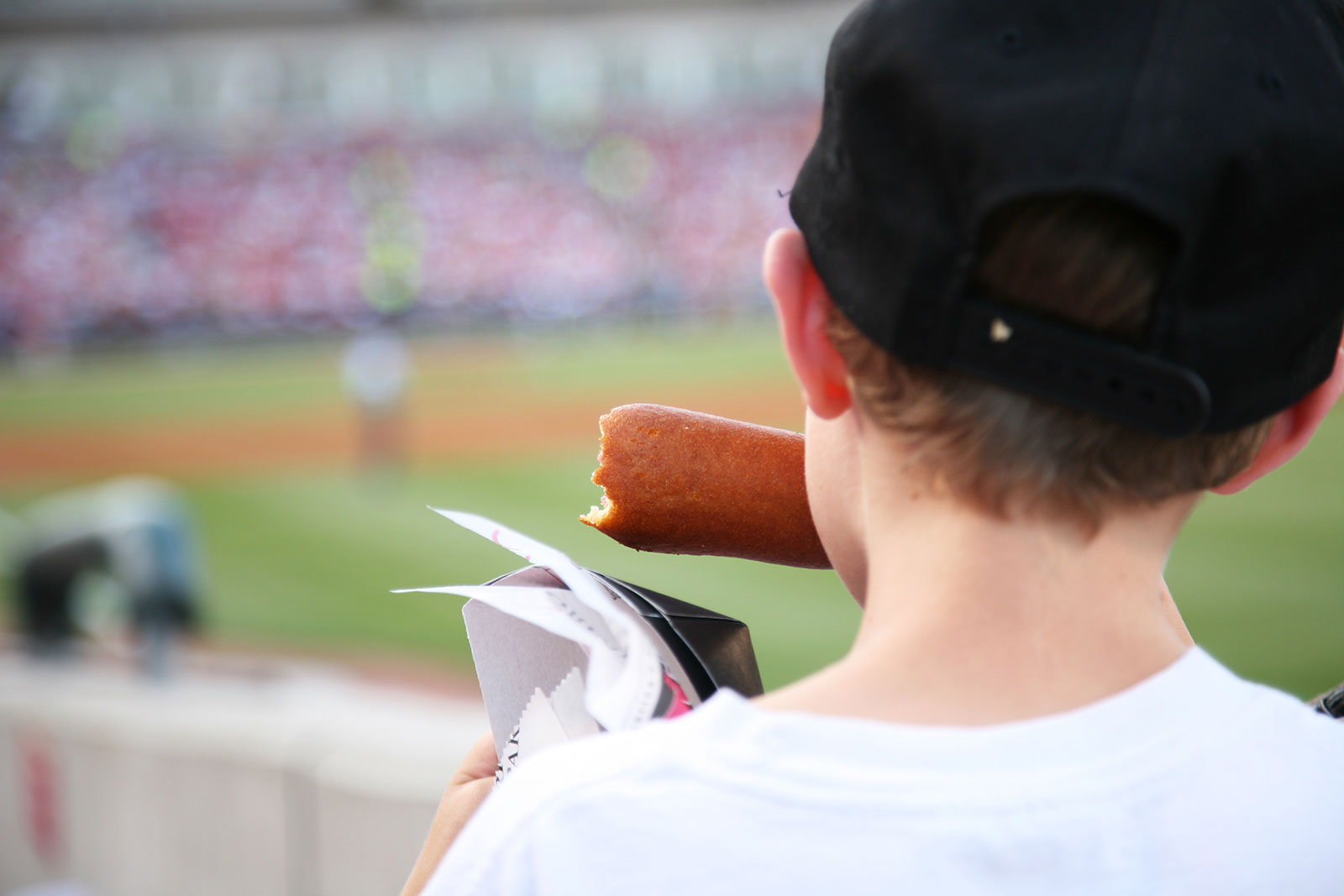 Child eating a corn dog at a baseball game